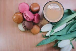 macaroons next to a cup of coffee and white tulips